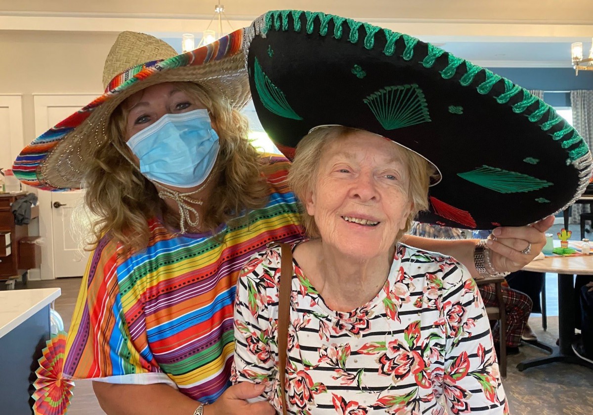 Two people wearing festive clothing and hats, smiling and enjoying a celebration.