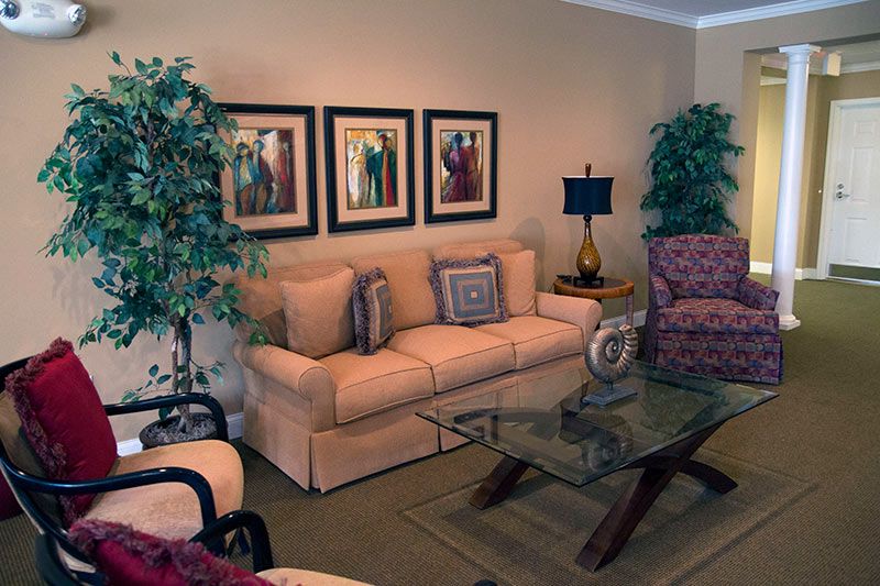 A cozy living room with a beige sofa, glass coffee table, and framed wall art.