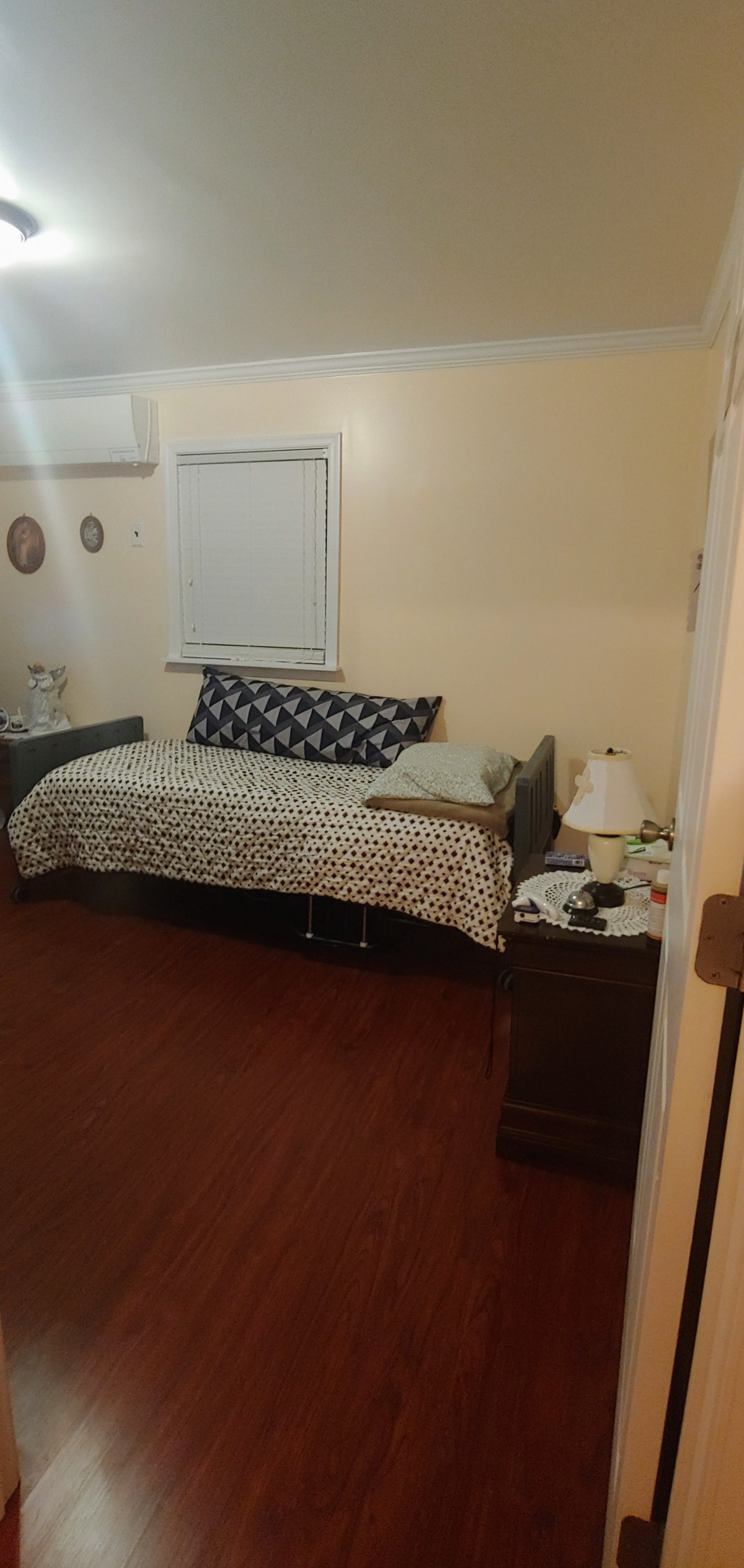 A cozy bedroom with a neatly made bed, nightstand, and lamp.