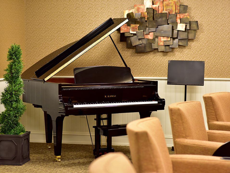 A grand piano in a cozy room with art on the wall and comfortable seating.