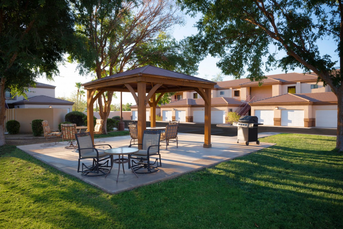 A cozy outdoor patio with a gazebo, surrounded by trees and greenery.