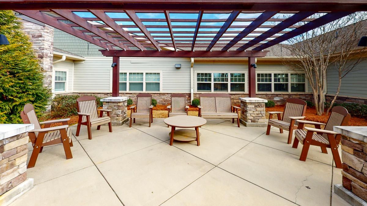A spacious outdoor patio with a pergola overhead, featuring comfortable seating and potted plants.