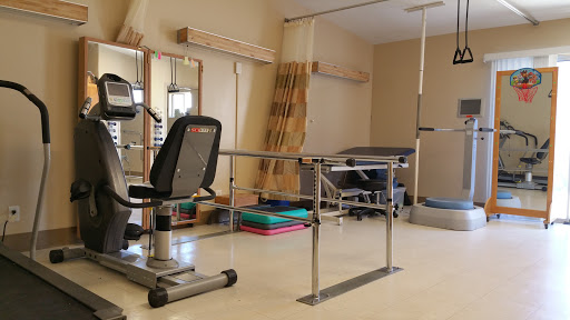 A well-equipped rehabilitation therapy room featuring exercise equipment and balance bars for patient assistance.