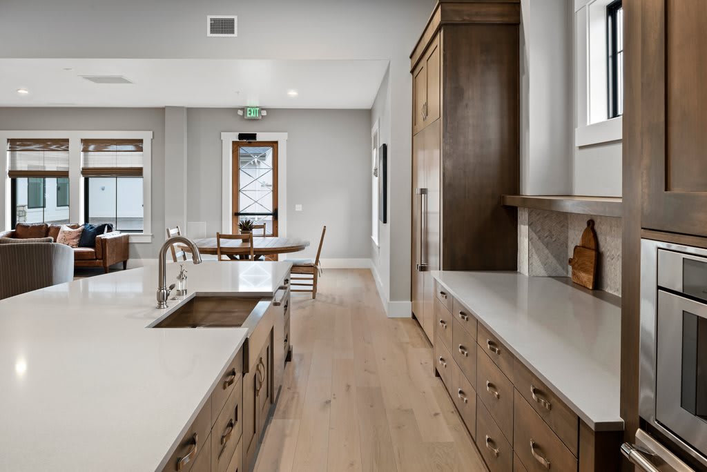 A modern kitchen with wooden cabinets and a dining area in the background.