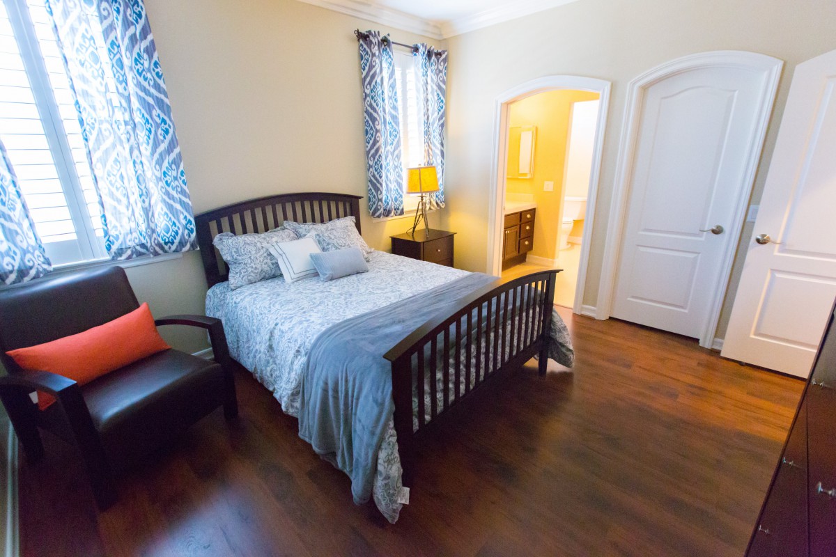 Cozy bedroom with a wooden bed, soft lighting, and hardwood flooring.