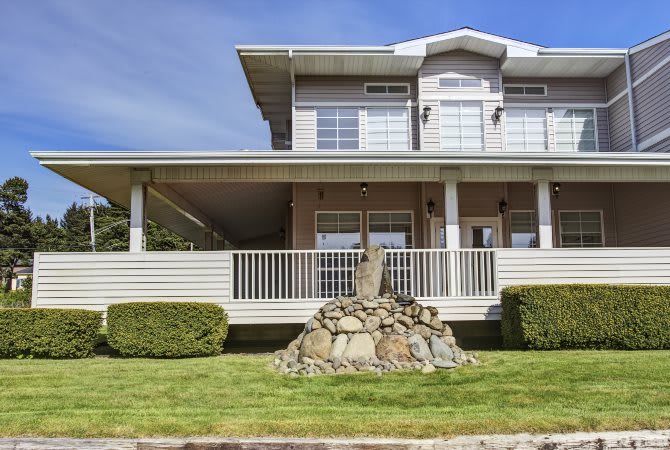 A two-story house with a spacious front porch and well-maintained lawn.