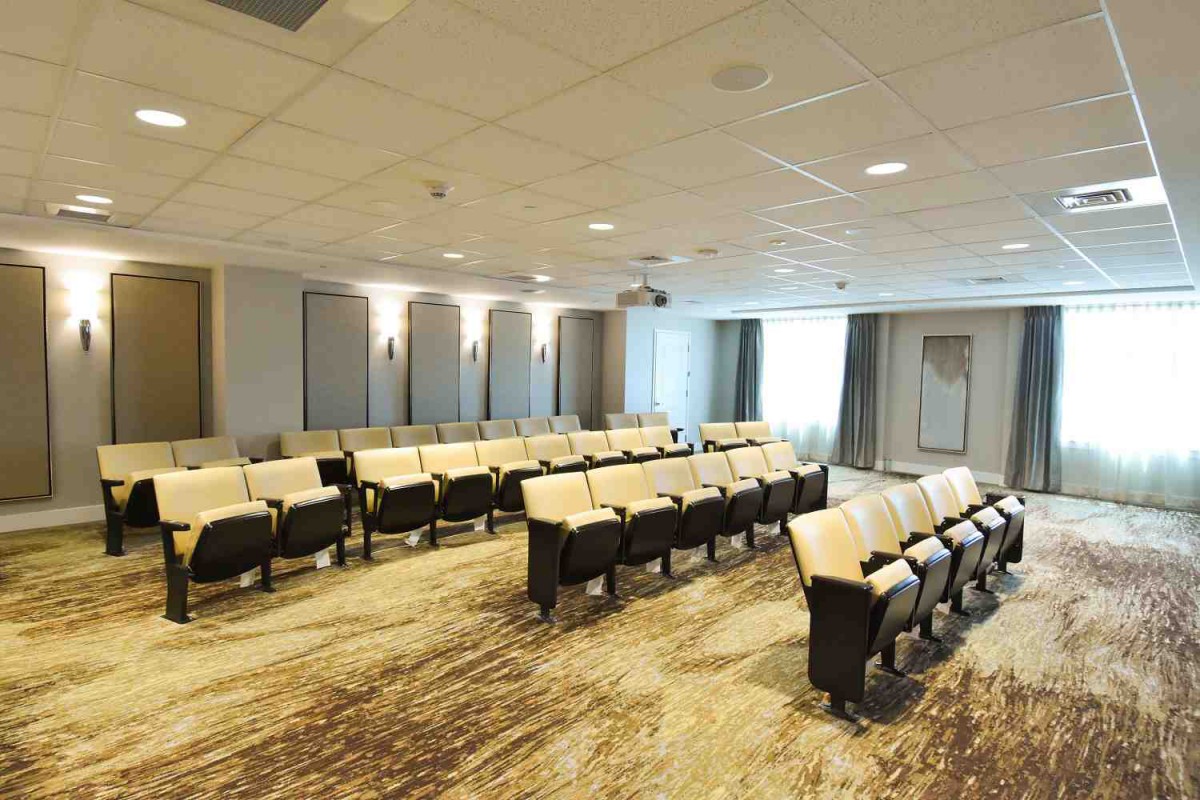 An empty conference room with arranged seating and a projector screen at the front.