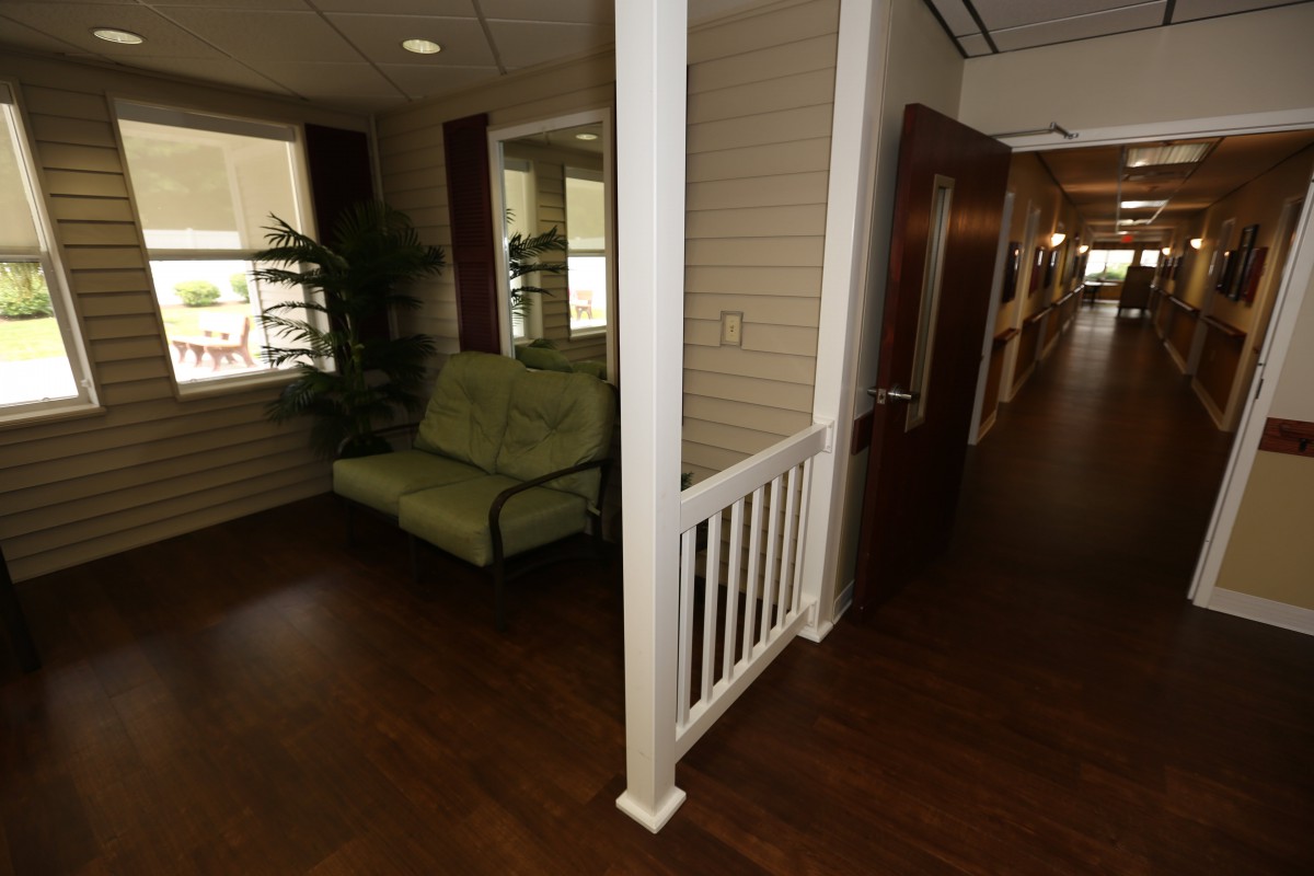 A cozy seating area with a sofa is situated in a hallway with wooden floors and decorative elements.