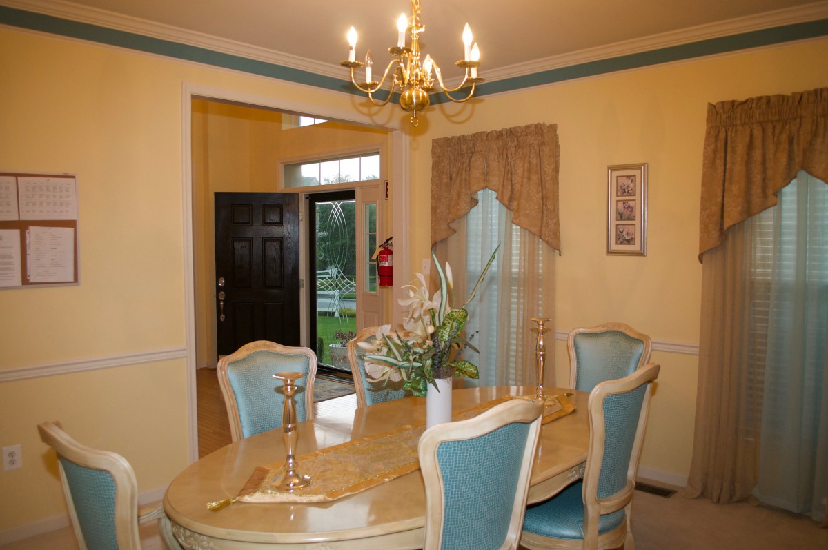 A traditional dining room with a chandelier, table, and upholstered chairs.