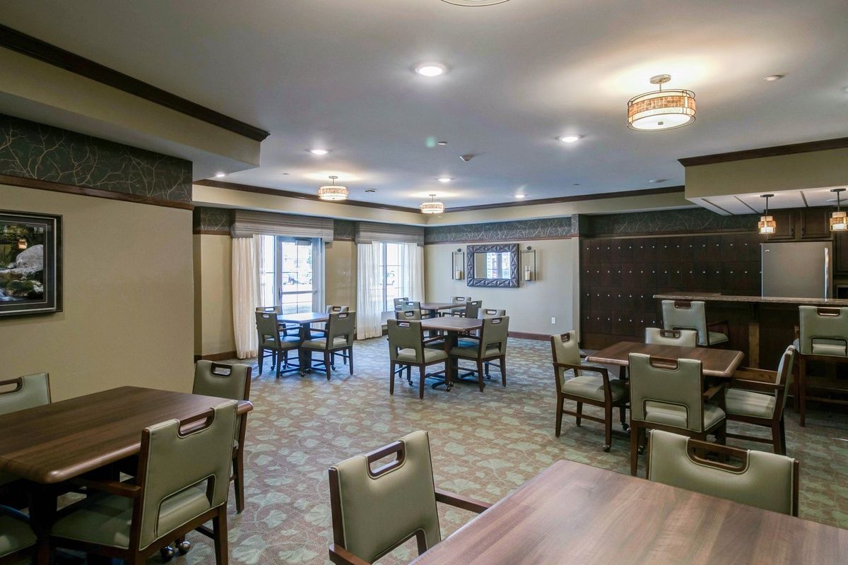A spacious dining room with neatly arranged tables and chairs, featuring ample natural light and stylish lighting fixtures.