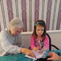 An elderly woman and a child working on a craft project at a table.