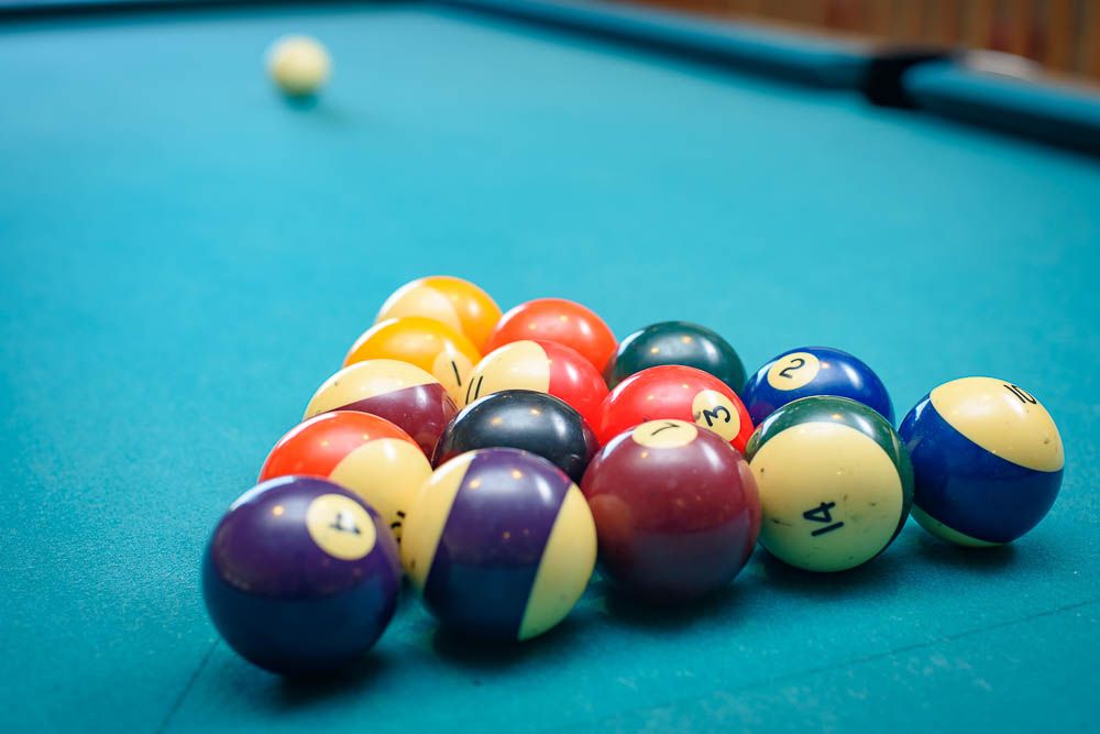 A neatly arranged set of pool balls ready for the break on a green billiard table.