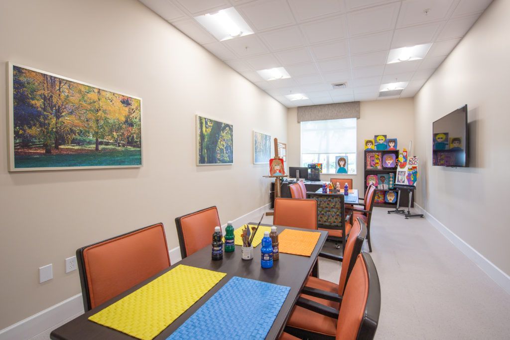A well-lit meeting room with a large table, colorful placemats, and artwork on the walls.