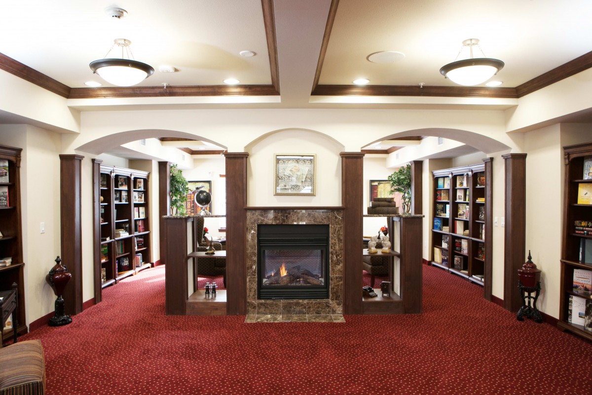 A cozy library interior with a fireplace and surrounding bookshelves.