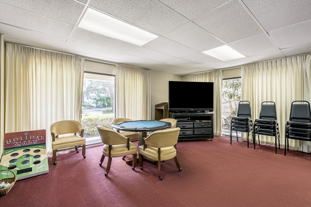A meeting room with a round table, chairs, and a large television.