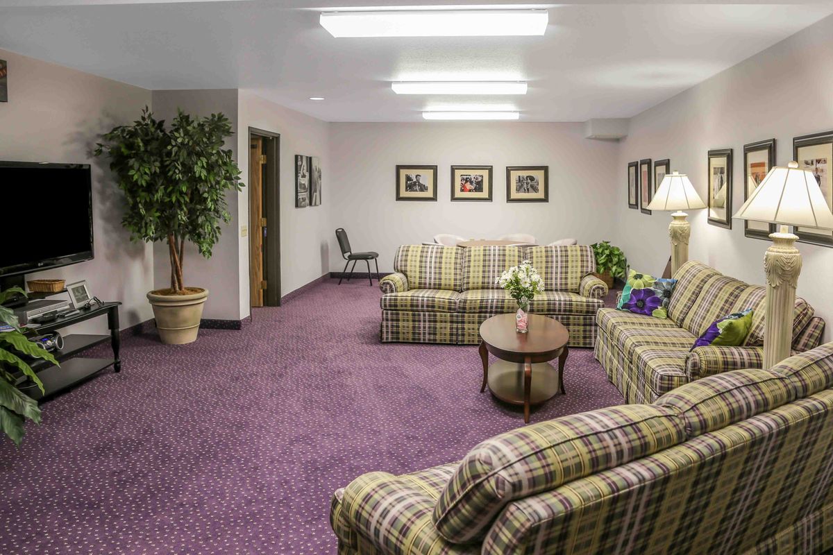 A cozy lobby area featuring plaid sofas, a coffee table, and framed artwork on the walls.