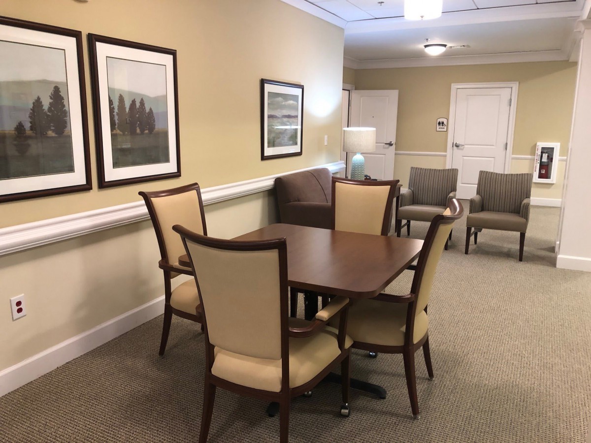 A well-appointed waiting room with a table, chairs, and framed artwork on the walls.