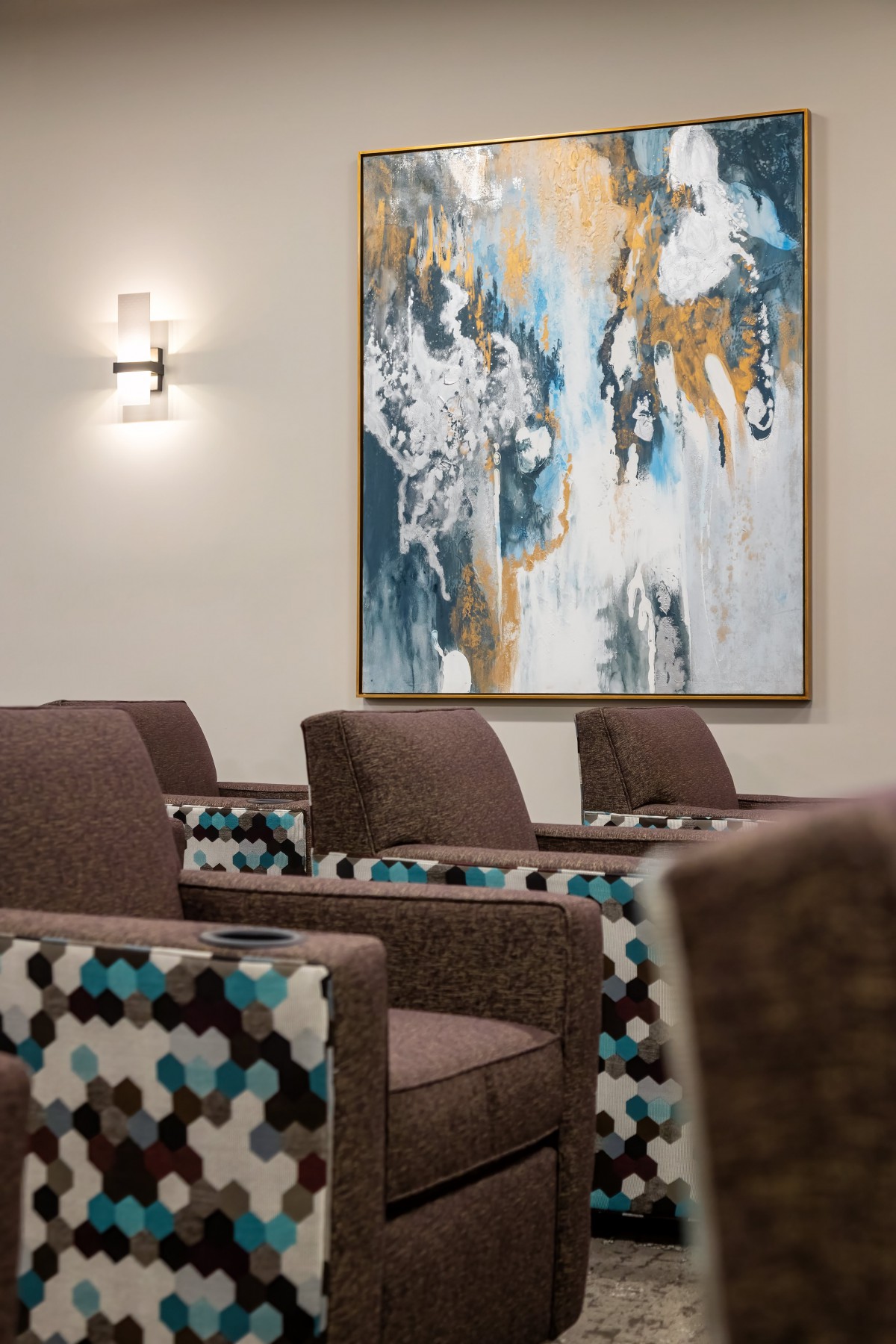 A modern interior with upholstered chairs and an abstract painting on the wall.