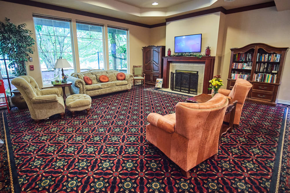 A cozy living room with a fireplace, comfortable seating, and large windows.