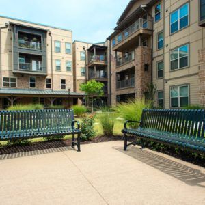 A modern apartment complex with outdoor benches and landscaped courtyard.