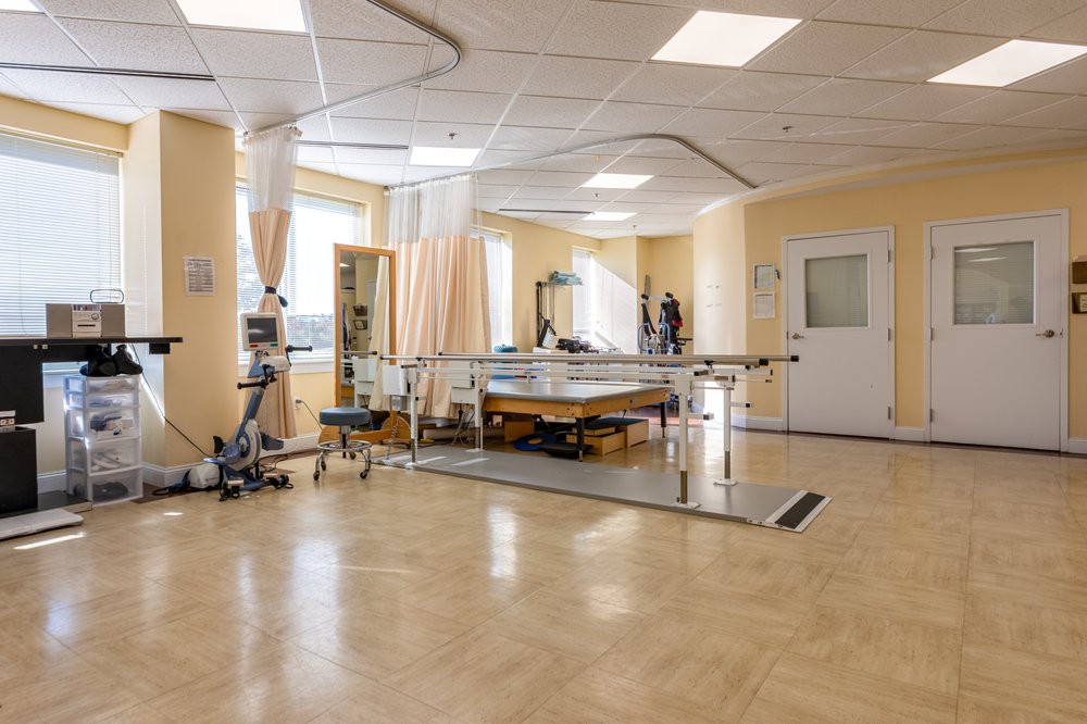 A spacious rehabilitation room equipped with various therapy and gym equipment in a medical facility.