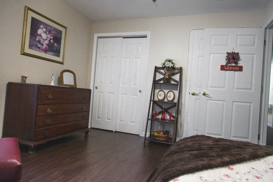 A cozy bedroom with a dresser and shelves for storage.