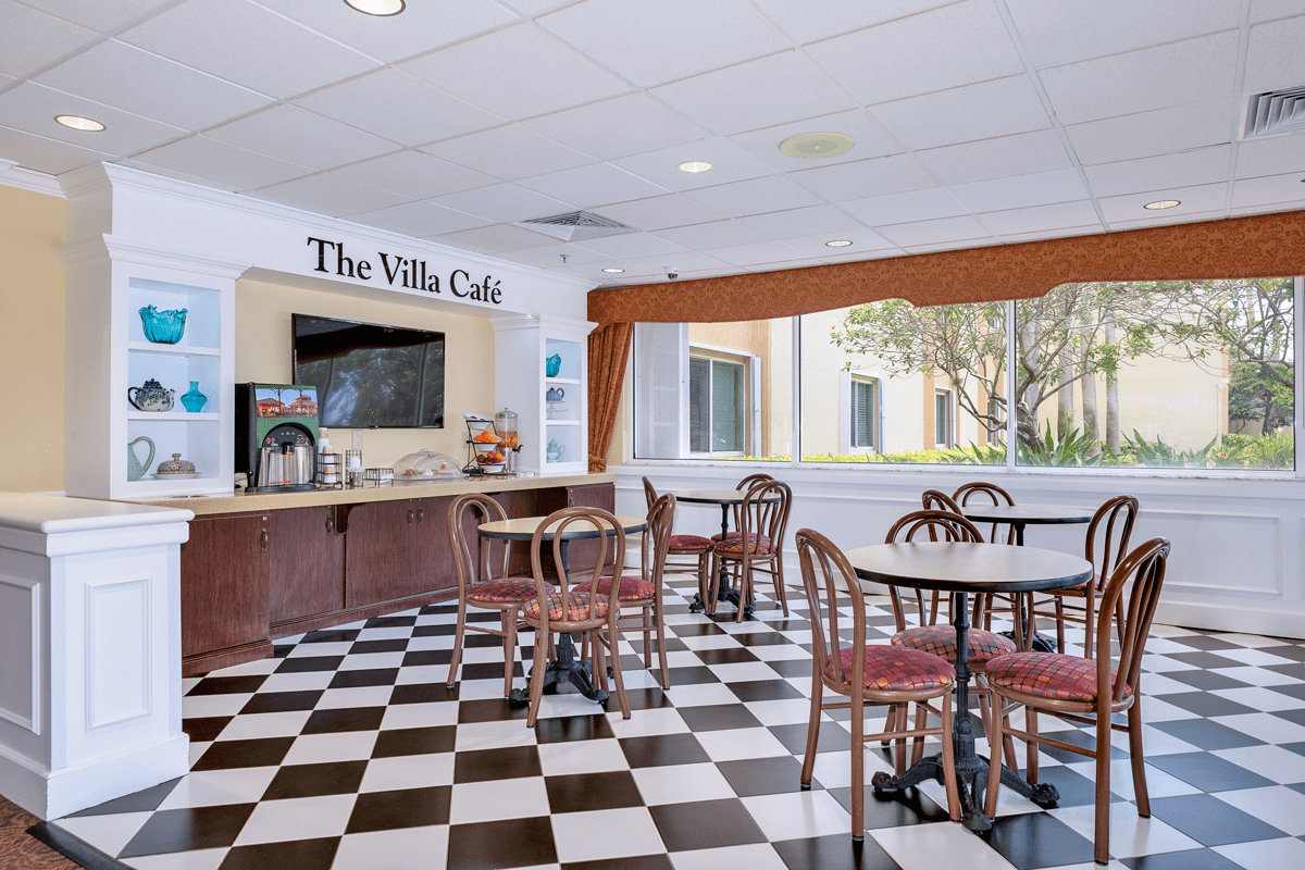 A cozy cafe with checkered flooring and multiple tables and chairs, creating a welcoming atmosphere.