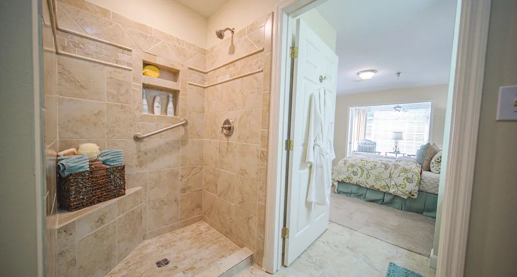 A modern bathroom with a tiled shower area and an adjacent bedroom.