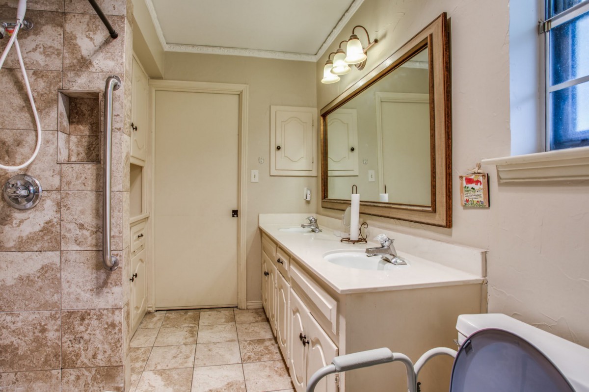 A clean and well-lit bathroom with a large mirror and double sinks.