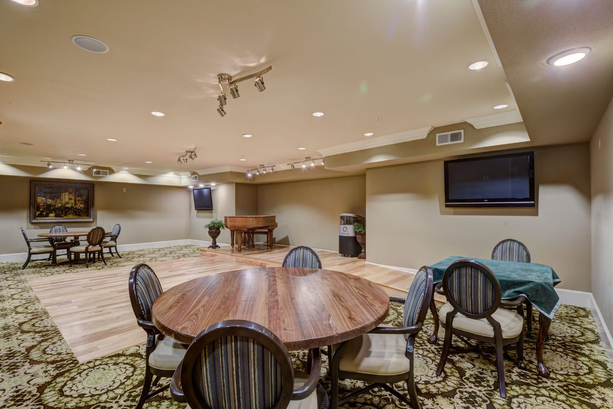 A spacious conference room featuring a round wooden table surrounded by chairs, with a projector and screen setup for presentations.