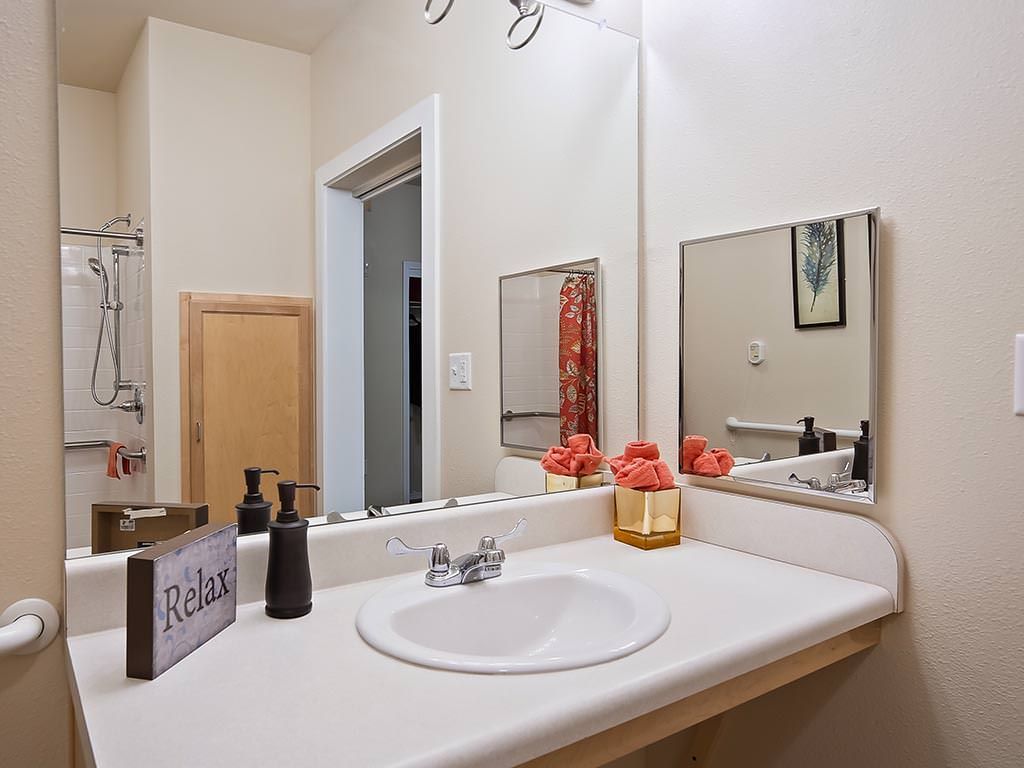 A tidy bathroom with a sink, mirror, and decorative items.