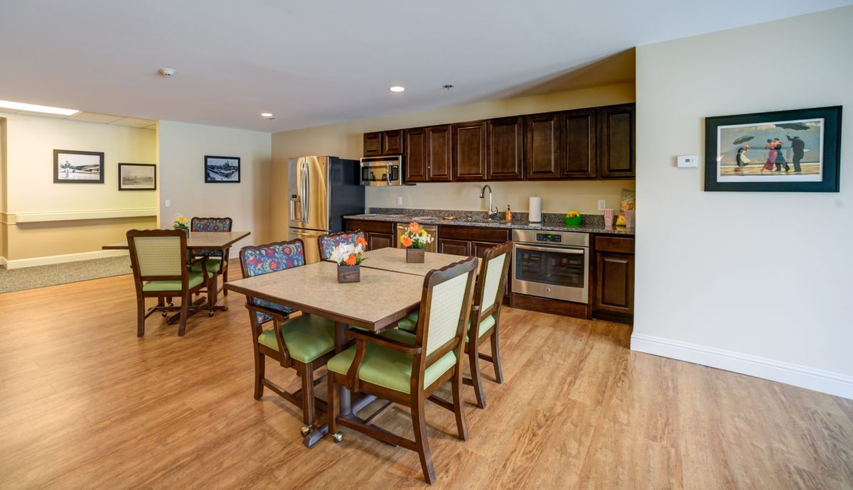 A modern kitchen with a dining area, featuring wooden flooring and stainless steel appliances.