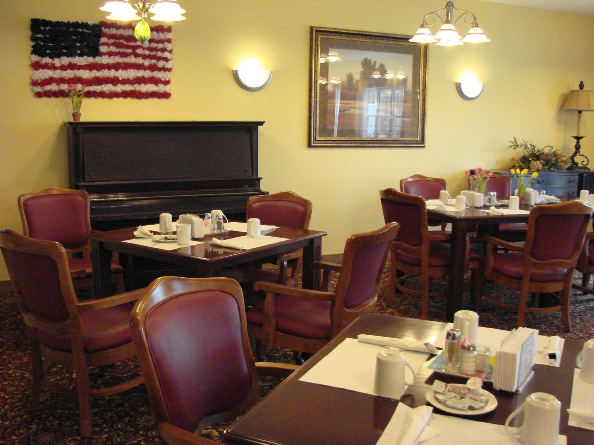 A cozy dining area in a restaurant with set tables, chairs, and a piano in the corner.