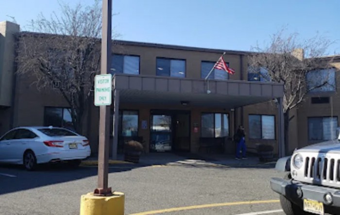 A building with an American flag flying outside, featuring a parking lot and entrance.