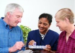 A nurse assisting two senior individuals with their medication.