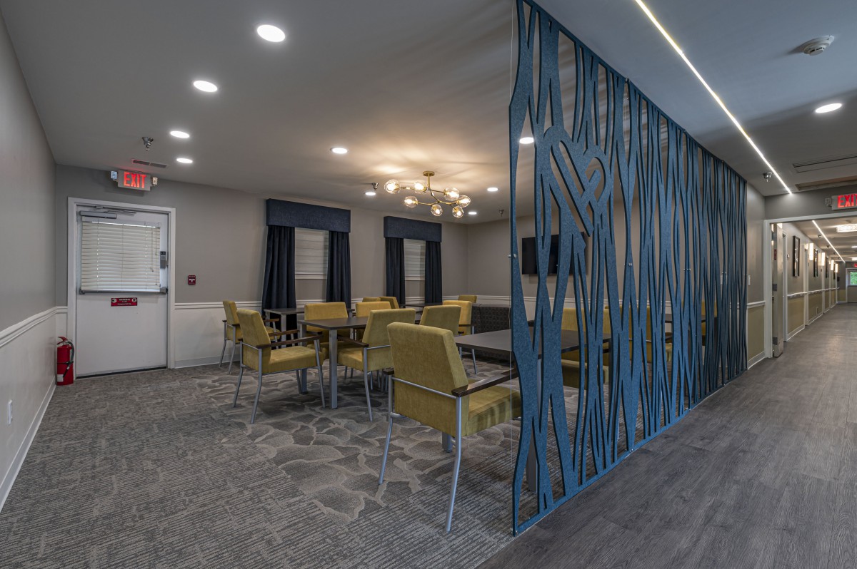 A modern dining area with yellow chairs and a decorative partition.