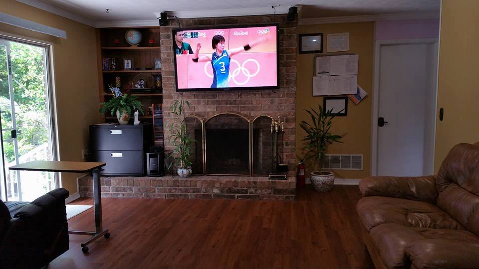 A cozy living room with a television displaying an Olympic sports event, set above a brick fireplace.
