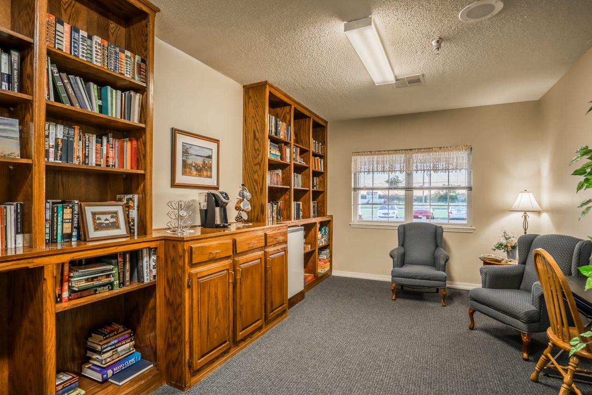 Cozy library room with wooden bookshelves and armchairs.