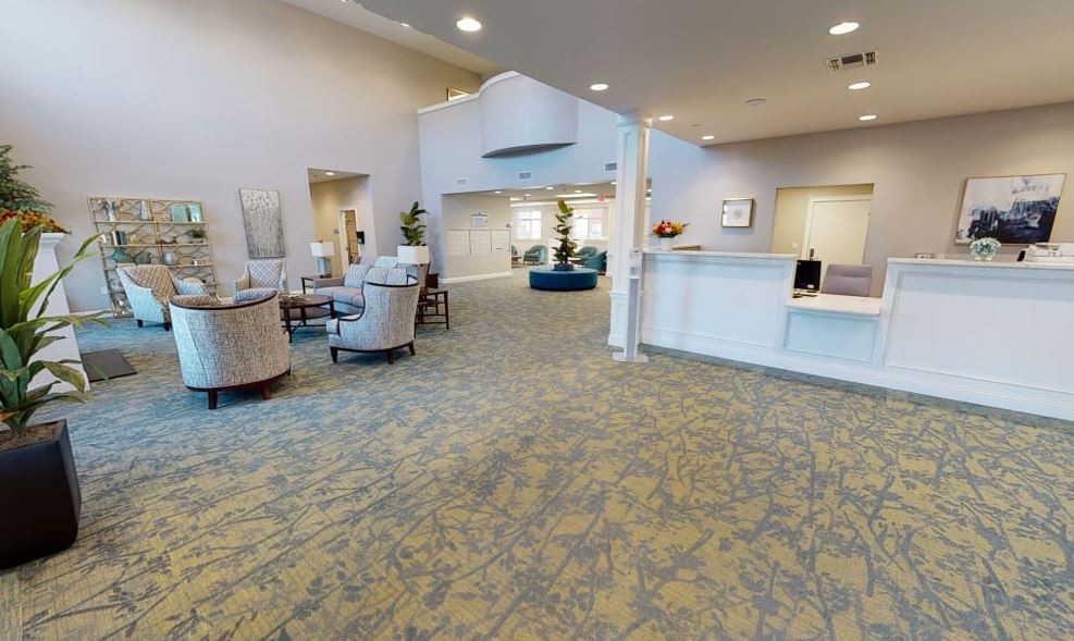 A spacious and well-lit lobby with a reception desk, comfortable seating, and indoor plants.