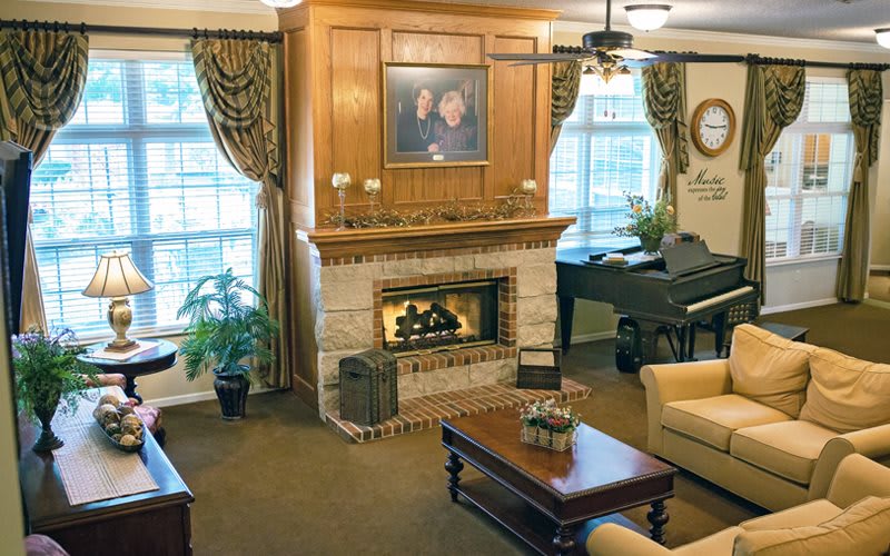 A cozy living room featuring a fireplace, piano, and elegant furnishings.