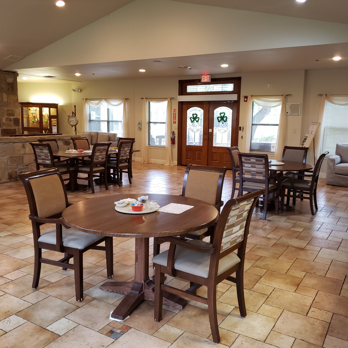 A spacious dining area with wooden tables and chairs, illuminated by soft lighting.