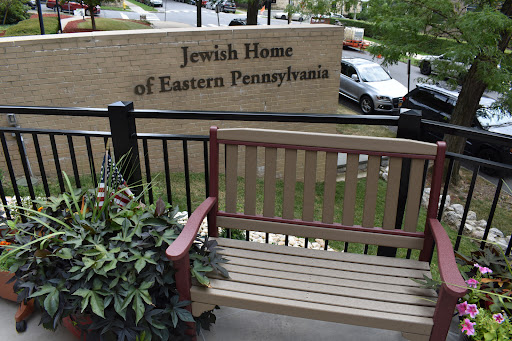 A view of the Jewish Home of Eastern Pennsylvania, featuring a bench in front of the building.