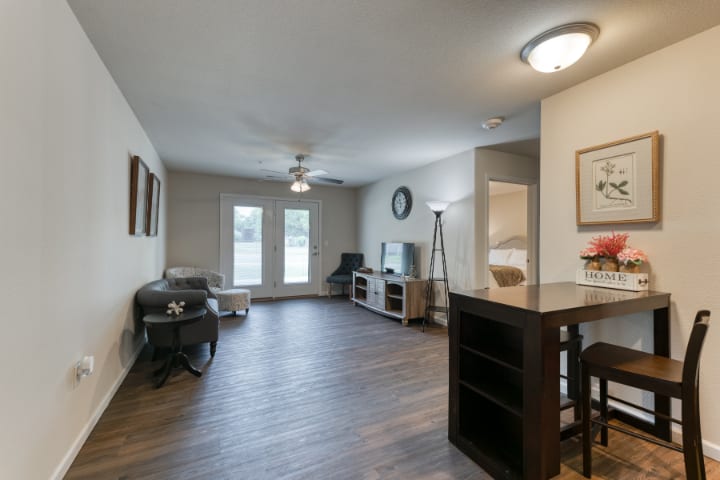 A spacious living room with modern decor, featuring wood flooring and a ceiling fan.