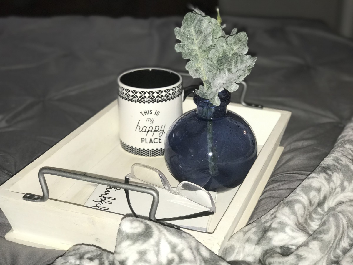 A cozy setup with a mug, vase, and glasses on a tray.