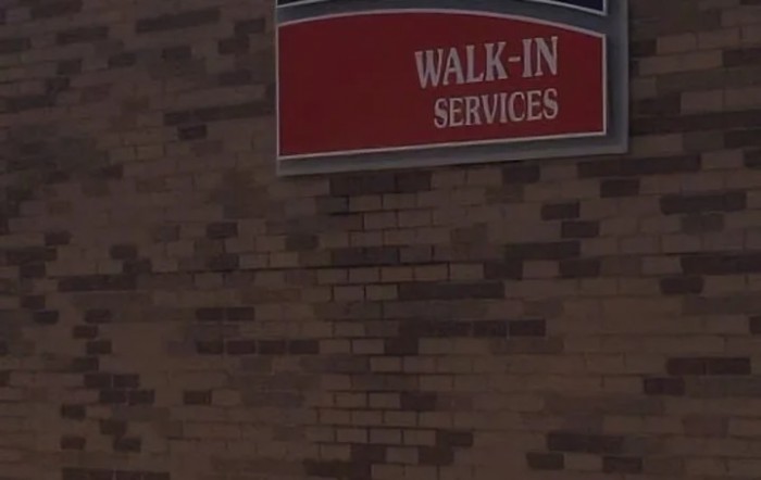 A sign on a brick wall indicating walk-in services.