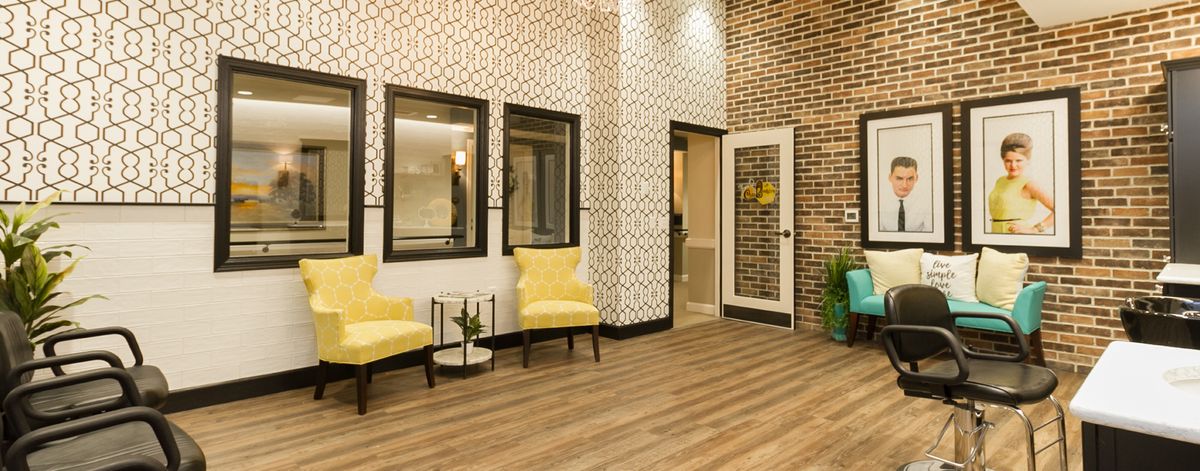 A modern waiting area featuring yellow chairs, a patterned wallpaper, and a wooden floor.