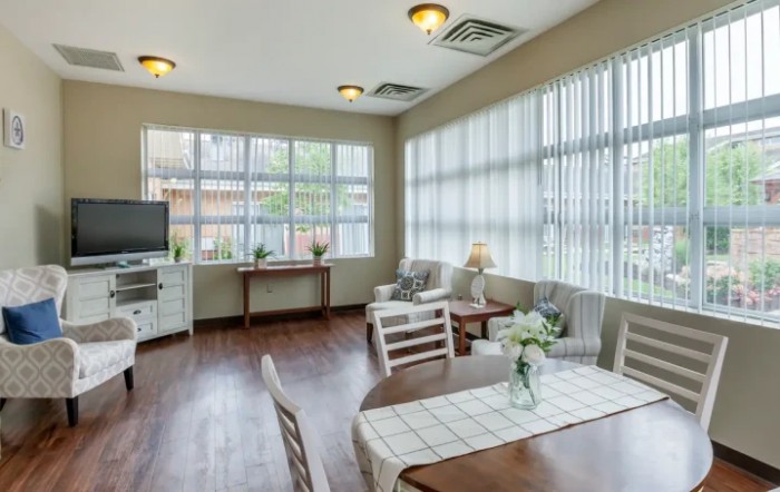 A bright and airy living room featuring large windows, wooden flooring, and comfortable seating.