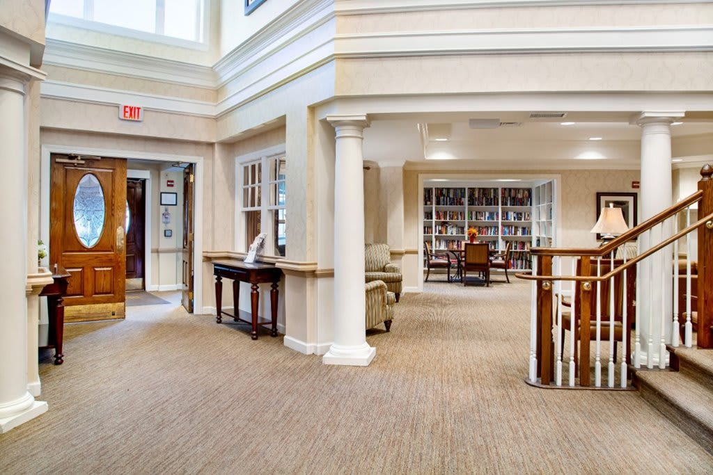 A spacious library interior with bookshelves, elegant columns, and comfortable seating.