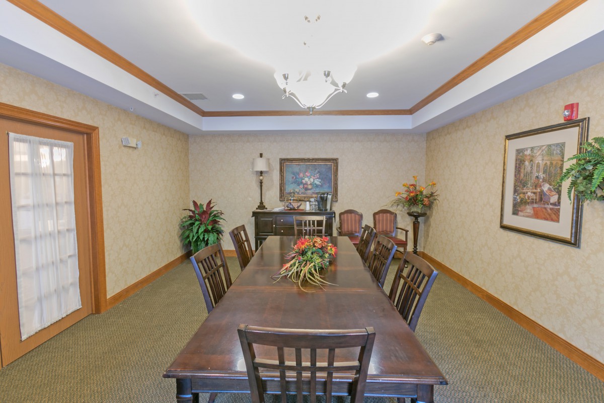 A formal conference room featuring a long table, chairs, and elegant decor.