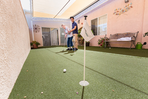 A man practicing his putting skills on an indoor golf green.